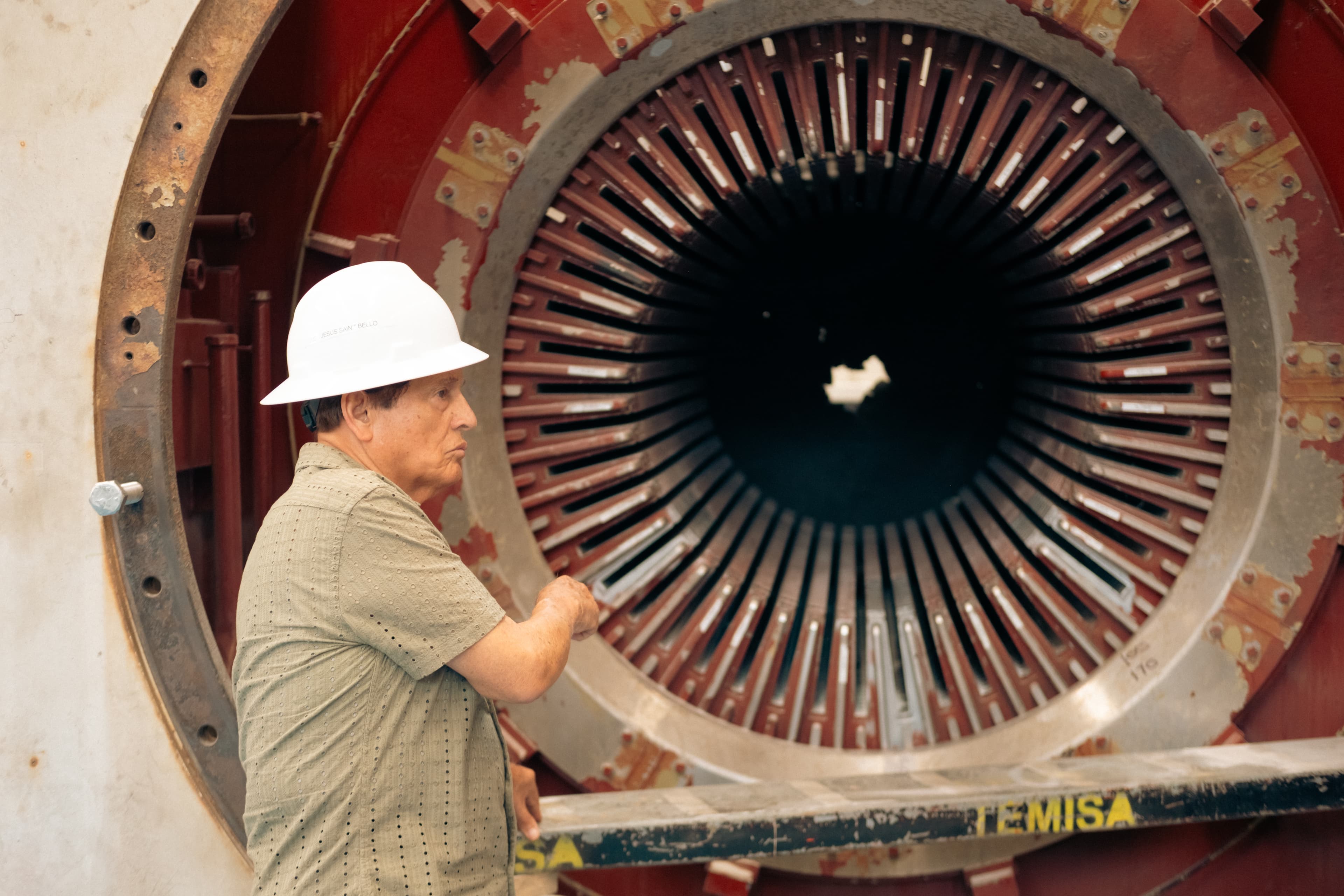 Don Jesús Sainz Bello con casco de seguridad TEMISA inspeccionando estator de generador eléctrico industrial gigante