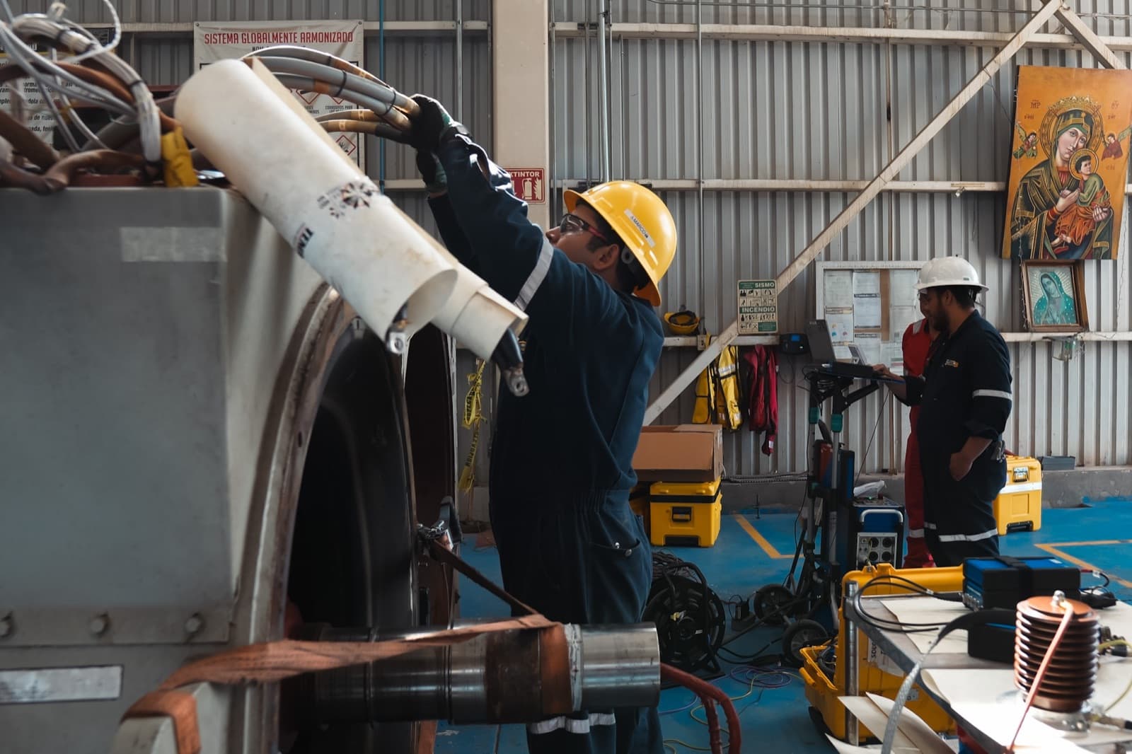 Técnicos TEMISA en mantenimiento mayor de un generador síncrono industrial IDEAL Electric en taller, con pruebas eléctricas en proceso — servicio para operadora oil & gas