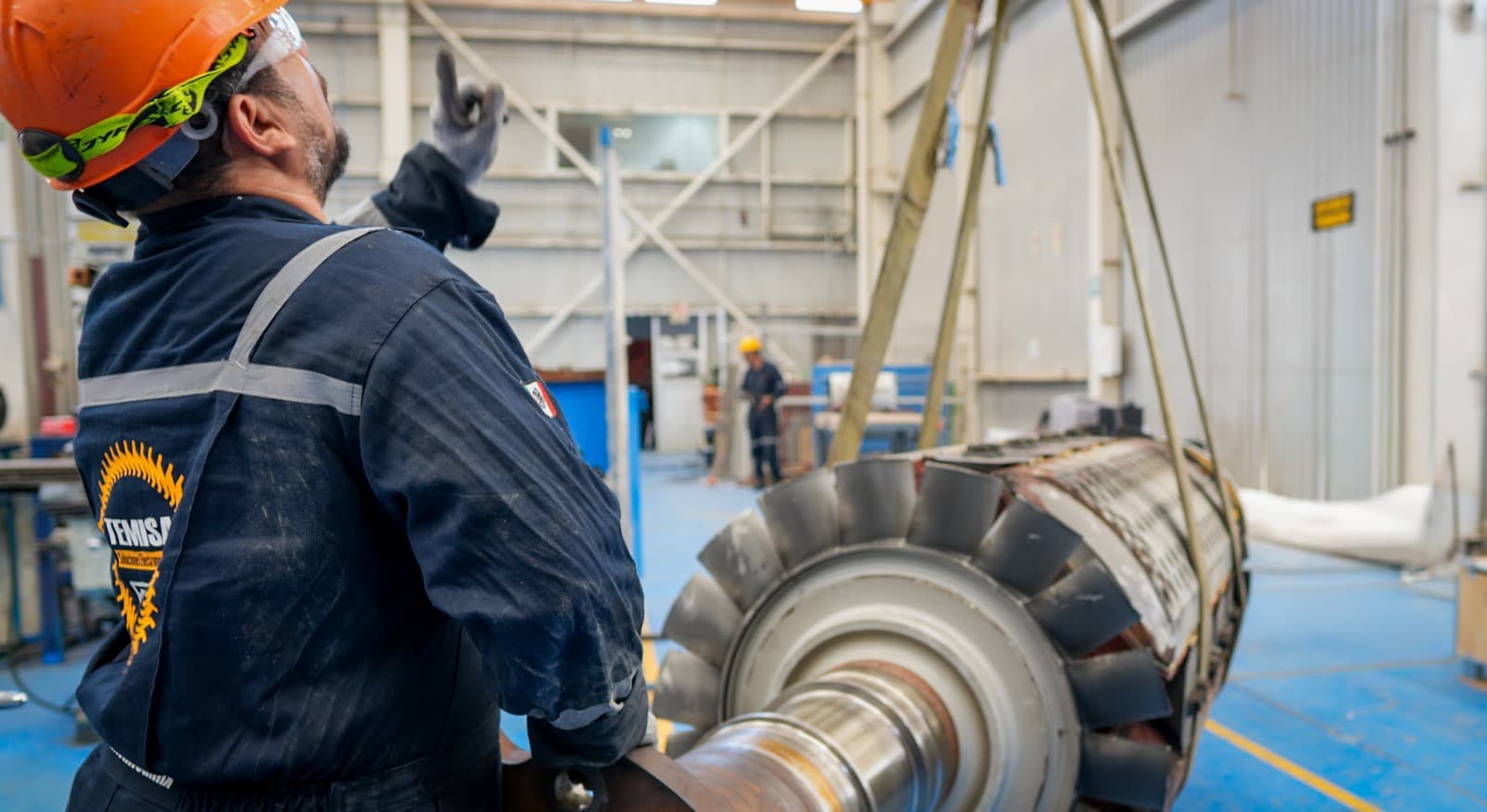Técnico TEMISA junto al rotor de un turbogenerador síncrono ABB izado con grúa viajera durante mantenimiento mayor L4 en taller — TEMISA Power Gen
