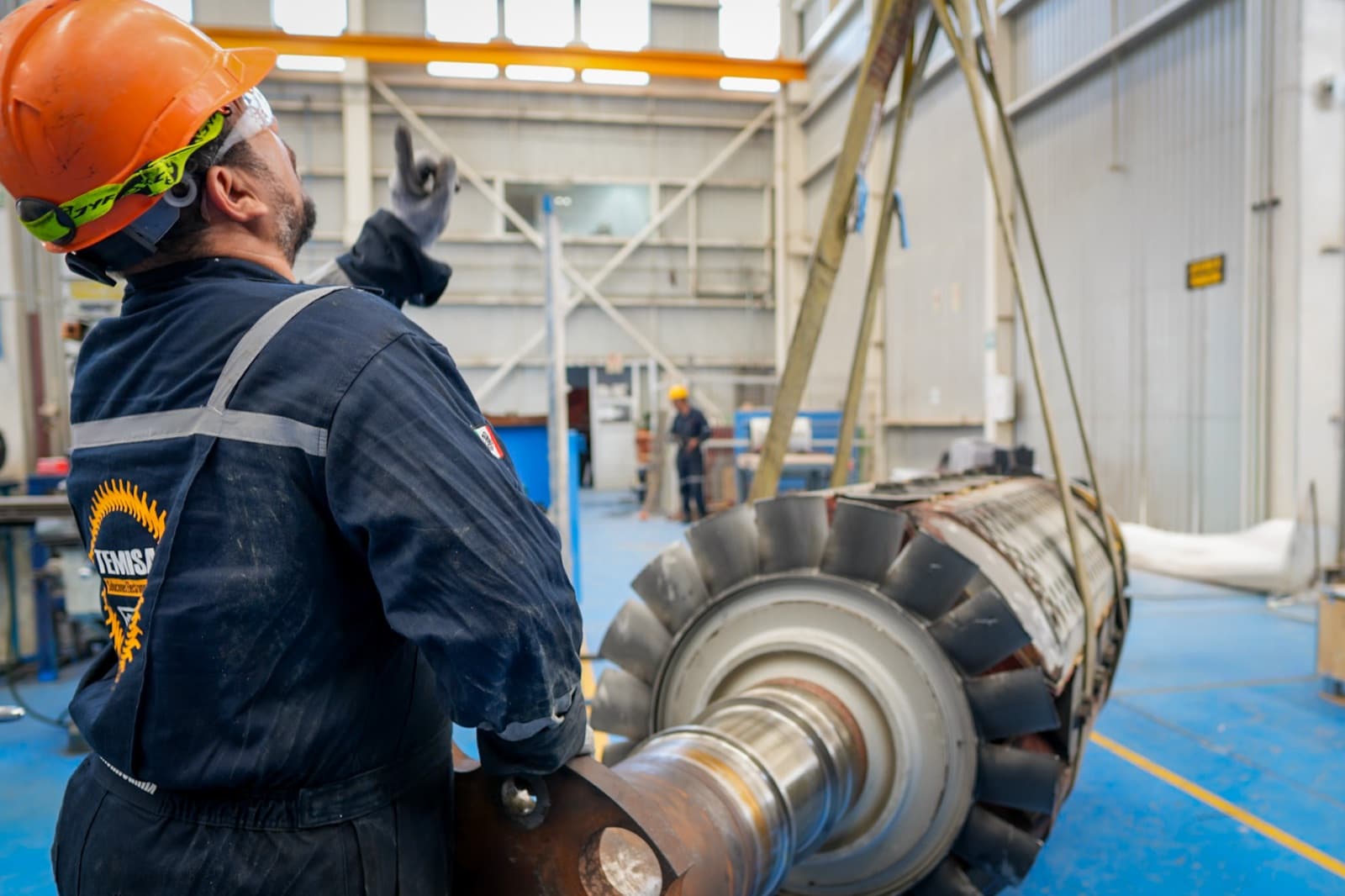 Técnico TEMISA junto al rotor de un turbogenerador síncrono ABB izado con grúa viajera durante mantenimiento mayor L4 en taller — TEMISA Power Gen