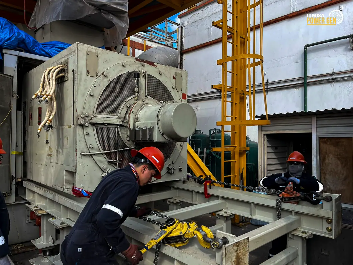 Técnicos accionando equipos de maniobra junto al generador sobre la estructura de apoyo.