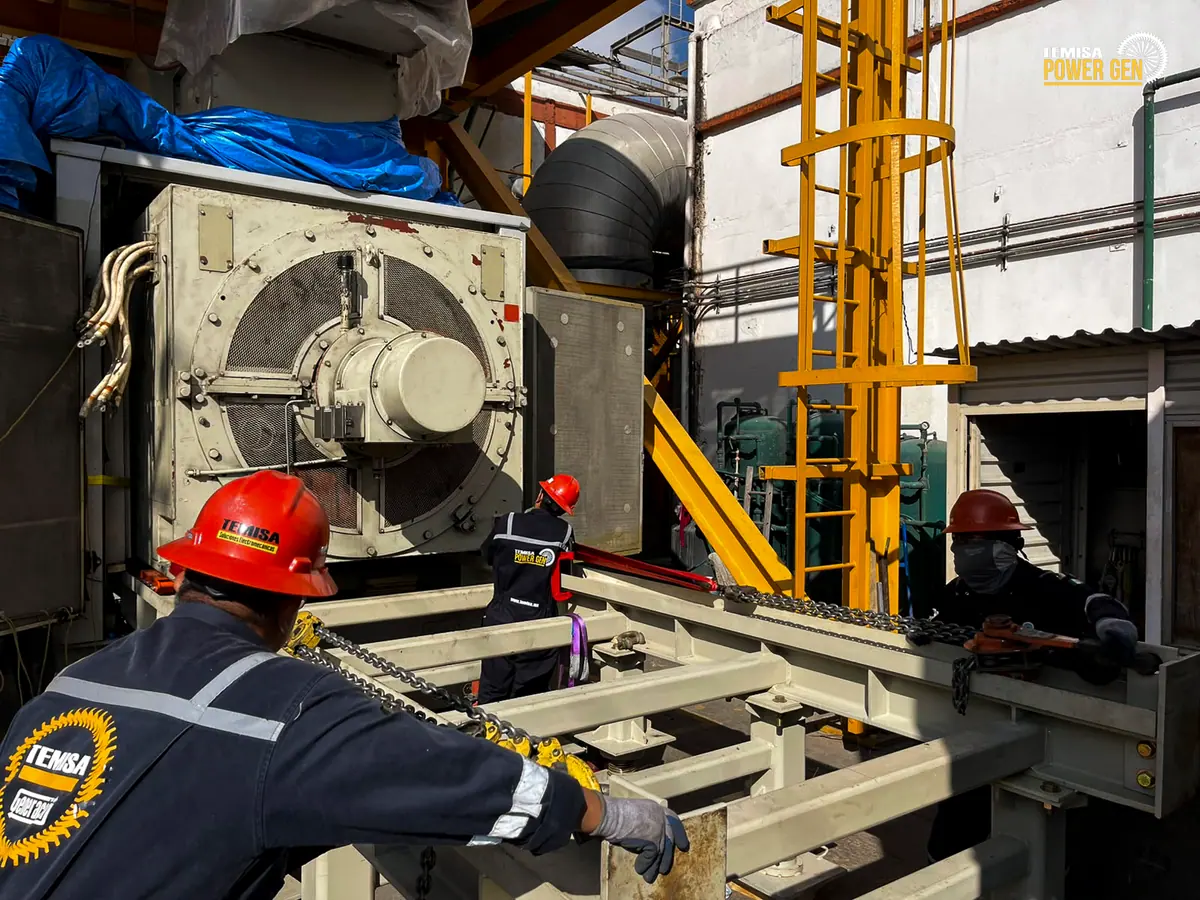 Personnel and handling equipment around the generator at the enclosure entrance.