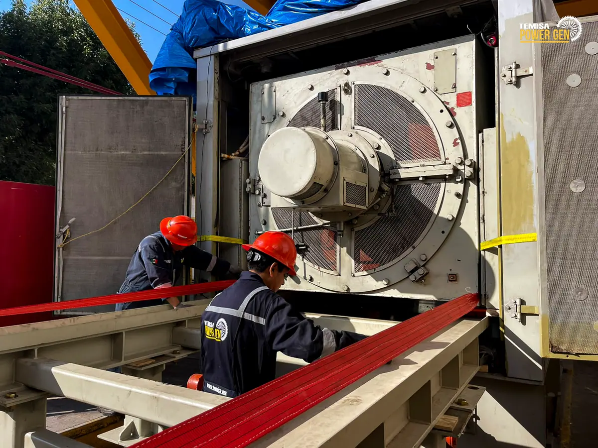 Close view of technicians, handling equipment and the support frame beside the generator.