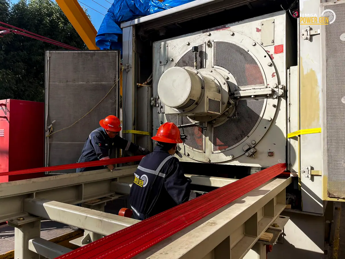 Two technicians beside the generator and auxiliary frame in front of the enclosure.